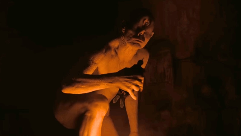 Polyphemus the cyclops crouching in the firelight in Nolan's The Odyssey